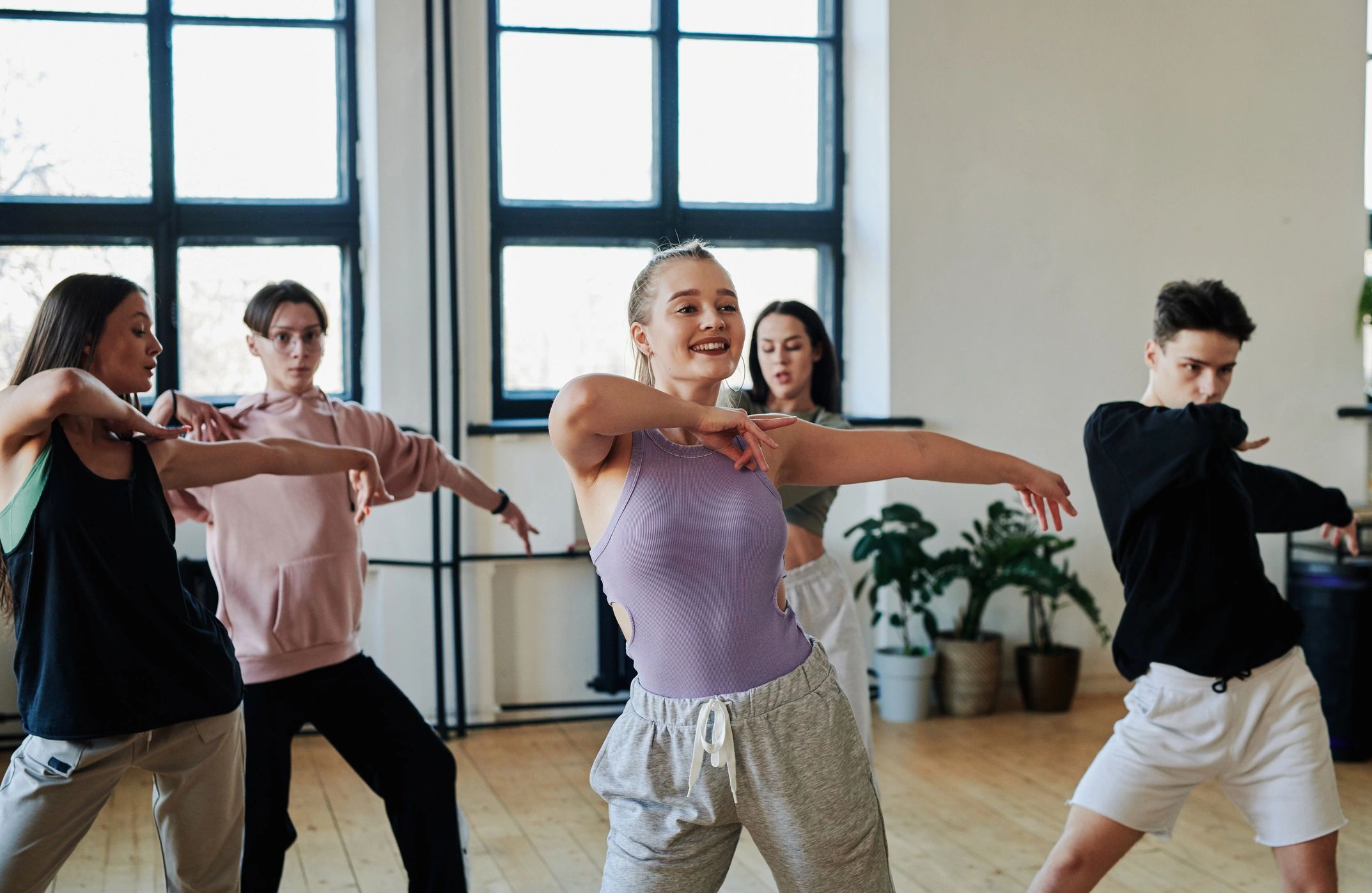 Dance instructor leading a teen group through choreography in a studio