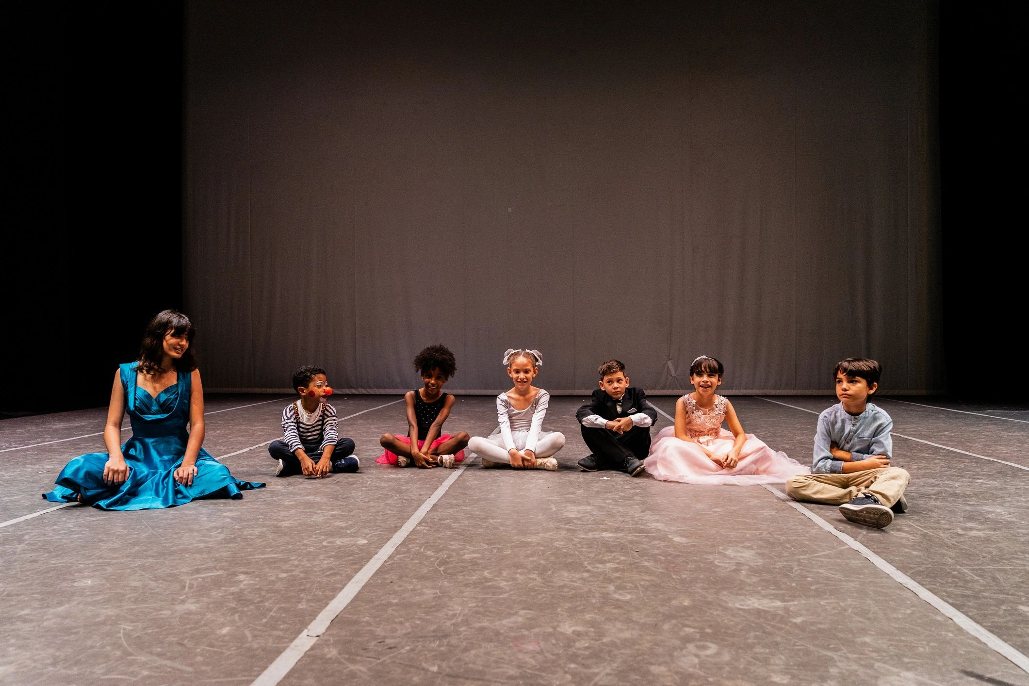 Young performers seated on a theater stage